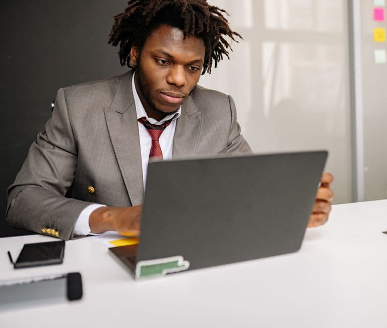 A focused entrepreneur or small business owner sitting at a modern desk with a laptop, viewing a sleek AI-generated website on screen, in a bright contemporary workspace with clean lines and bold accent colors reflecting innovation and tech confidence
